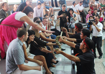 Foreign tourists excitingly touching a python