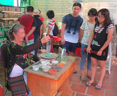 Young people watching artisan Hong Chau Sa making sand pictures.