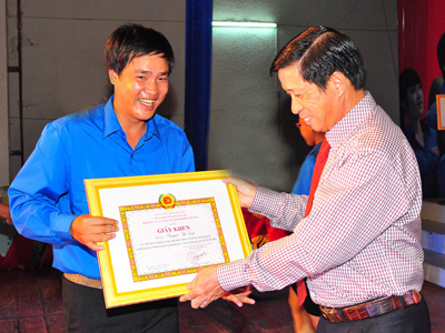 Luong Kien Dinh offering certificate of merit to a typical young Party member.