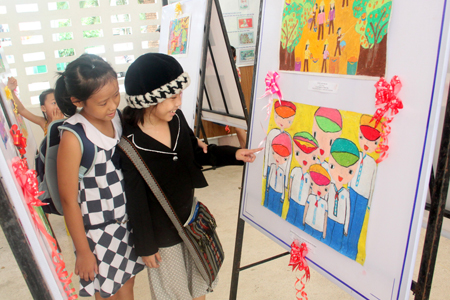 Children watching paintings displayed at the exhibition.