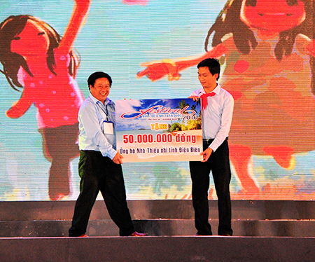 Representative of Khanh Hoa Provincial Children’s House offering proceeds from auction to Central Council of Young Pioneer Organization.