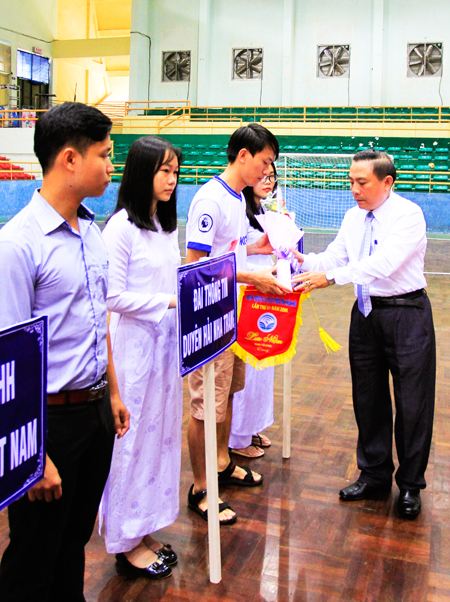 Leader of Khanh Hoa Provincial Department of Information and Communications offering flags and flowers to participating units.