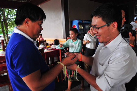 Members of two units tying threads around each other’s wrist.