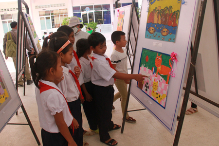 Children contemplating paintings at exhibition.