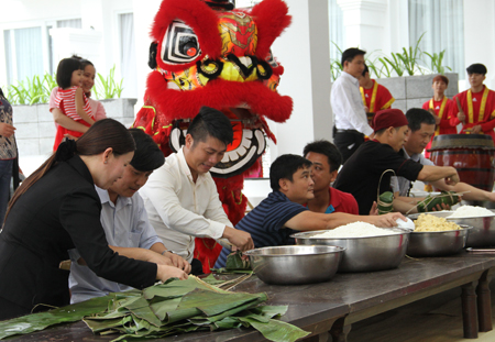 Tourists wrap Vietnamese Tet cakes eagerly.