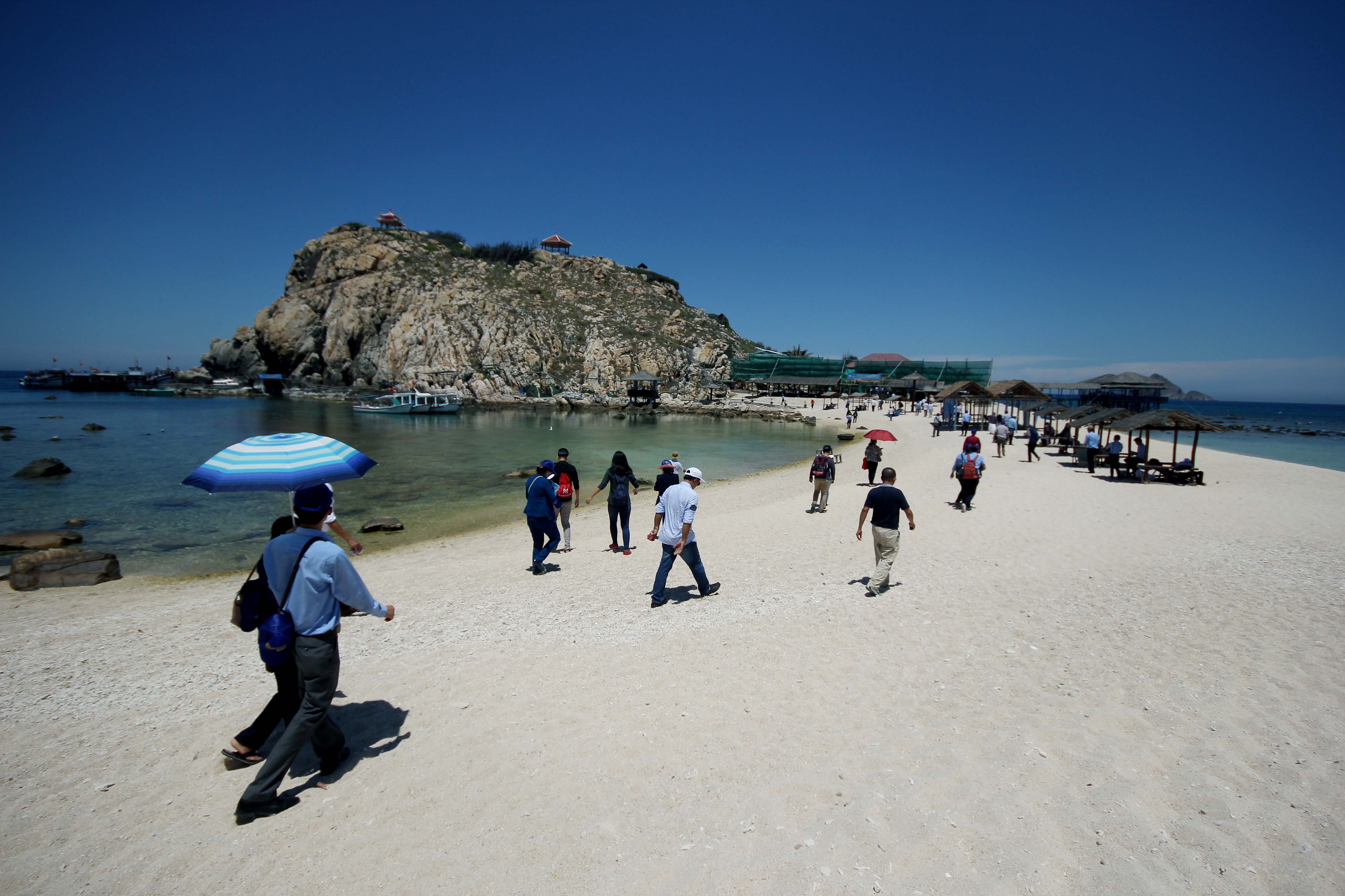 Tourists walking on path parting sea into two beaches 