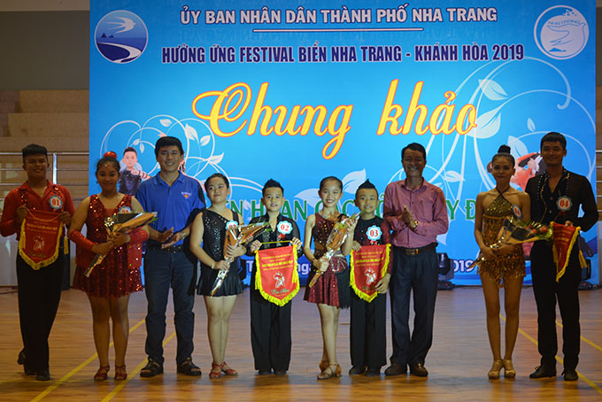 Organization committee giving flowers and flags to dance couples