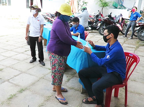 People washing hands with hand sanitizer before receiving rice