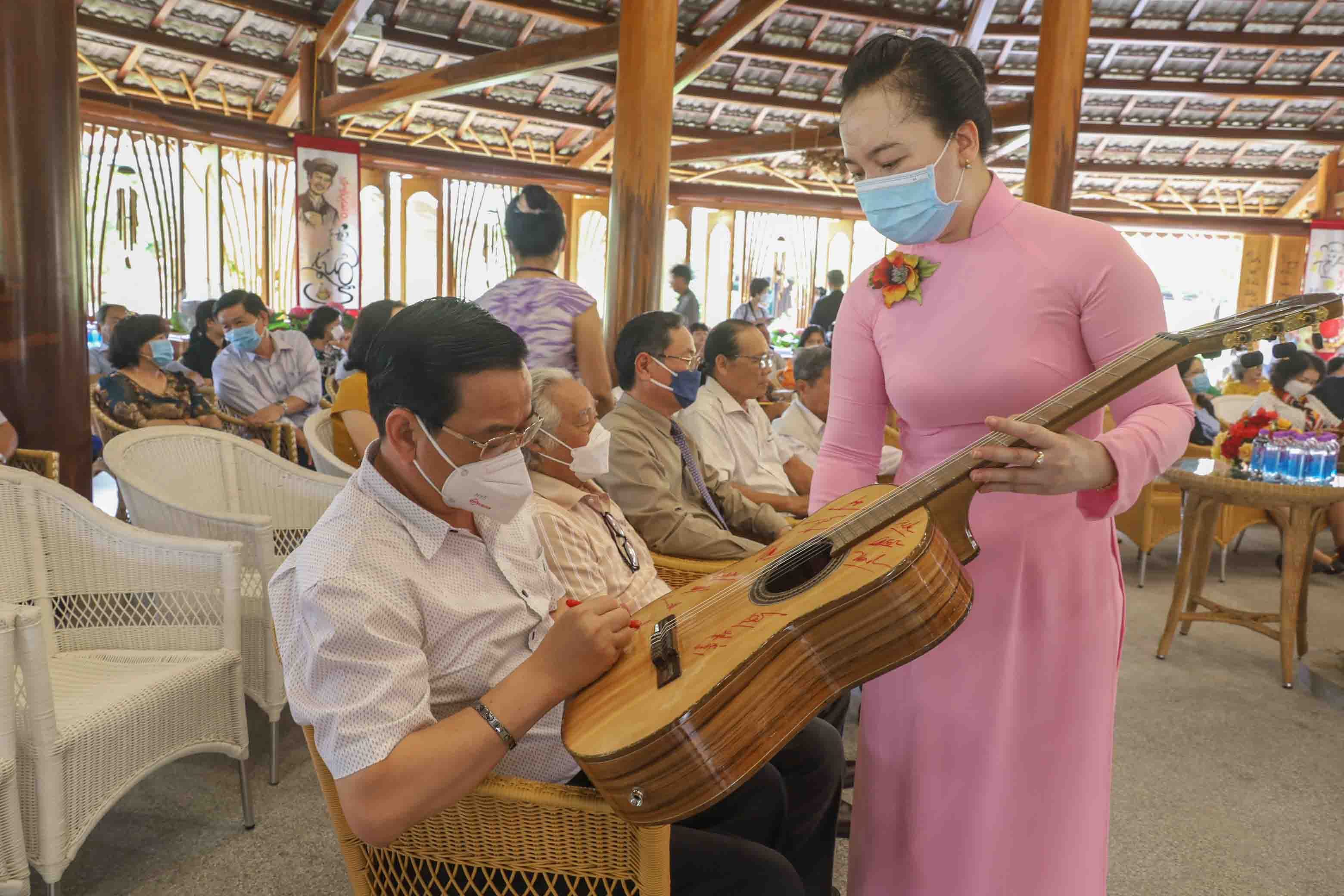 Representatives sign the acoustic guitar made by artisans of Truong Son Craft Village during COVID-19