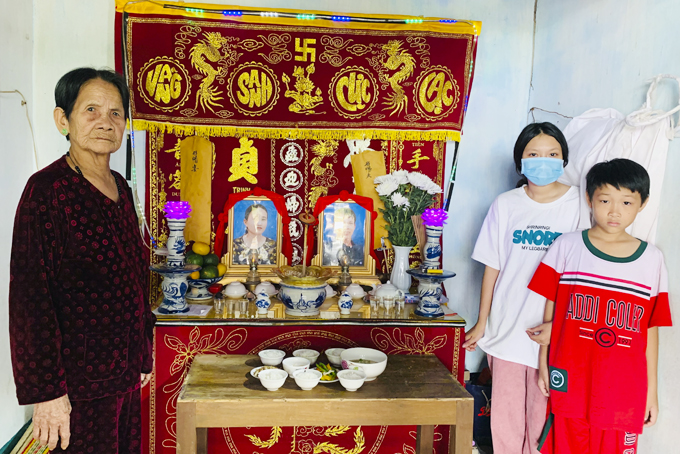  Sister and brother Tram Anh, Gia Huy and their grandmother by their parents’ altar